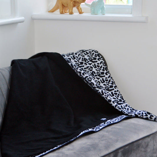 Our black and white dino camo print soft cotton blanket with a black minky fleece backing. 